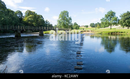 Footbridge and stepping stones across River Wharfe at Bolton Abbey, North Yorkshire Stock Photo