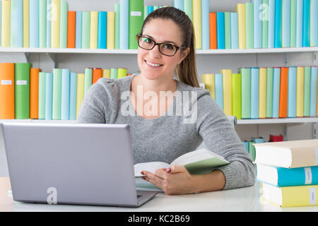Young Happy Woman Using Laptop In Library Stock Photo