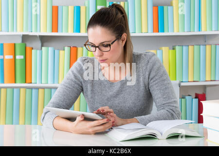 Young Woman Using Digital Tablet In Library Stock Photo