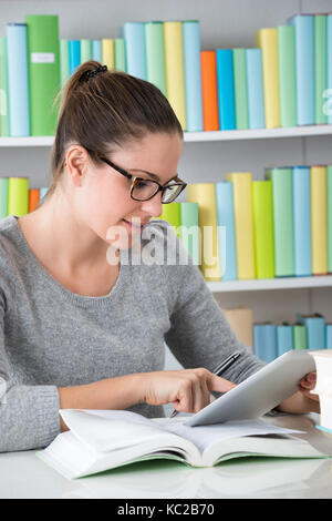 Young Woman Using Digital Tablet In Library Stock Photo
