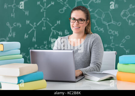 Young Woman Using Laptop At Desk In Classroom Stock Photo