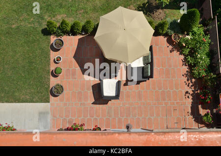 Bird's eye view of garden furniture under parasol surrounded by garden plants Stock Photo