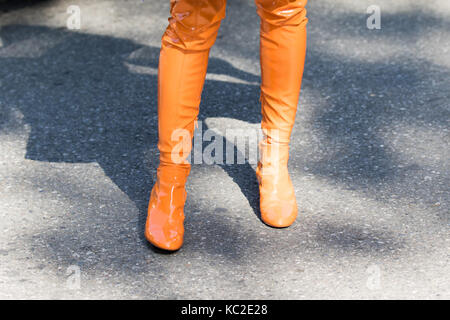 Milan, Italy - September 22, 2017: Model wearing a pair of orange high boots during the Armani parade, photographed on the street Stock Photo