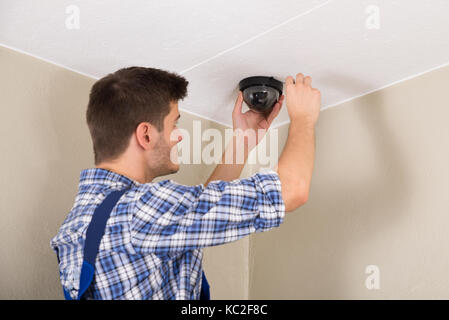 Young Male Technician Installing Surveillance Camera On Ceiling Stock Photo