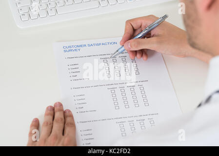 Close-up Of Person Hands Filling Survey Form With Pen Stock Photo