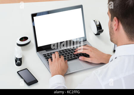 Close-up Of Businessman Working On Laptop Showing Blank Display At Desk Stock Photo