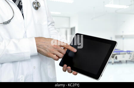 Smart healthcare technology concept. Doctor point finger to black screen tablet with blur hospital background. Stock Photo