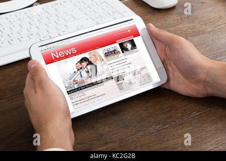 Close-up Of Businessperson Hands Holding Mobile Phone Showing News Stock Photo