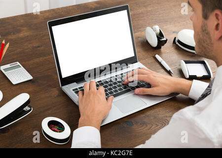 Close-up Of Businessperson Working On Blank Display Laptop At Desk Stock Photo