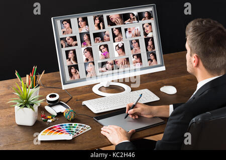 Male Photo Editor Using Graphic Tablet While Working With Computer Stock Photo