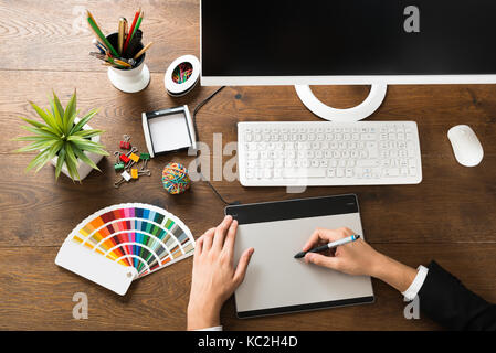 Young Male Designer Using Digital Graphic Tablet With Stylus At Desk Stock Photo
