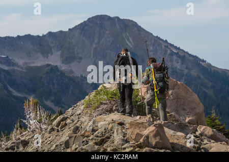 Climbers on the moraine overlooking Blue Glacier and Mount Olympus in the dramatic setting at the end of the Hoh River Trail in Olympic National Park, Stock Photo