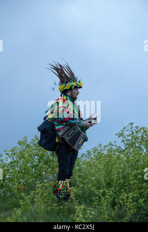 Lone watcher in costume at dawn on May Day on the West Hill in Hastings, East Sussex, England Stock Photo