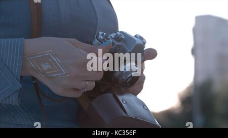 Girl's hands hold the vintage old film camera. Girl camera shutter clicks close up Stock Photo