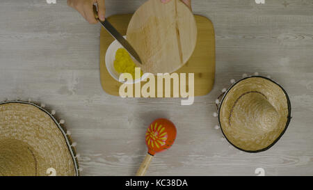 Puts food in the dish with a knife. On the table is the two Mexican hats, maracas, abstraction for instagram Stock Photo