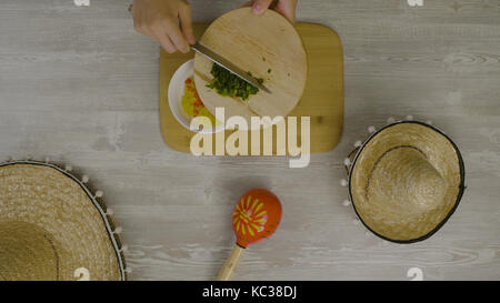 Puts food in the dish with a knife. On the table is the two Mexican hats, maracas, abstraction for instagram Stock Photo