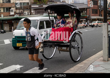 Kyoto, Japan -  May 17, 2017: Traditional human power rickshaw carrying women in kimono Stock Photo