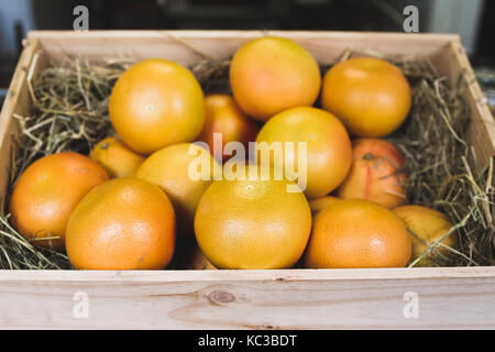 Wooden box with fresh ripe grapefruits on display in a fruit shop Stock Photo