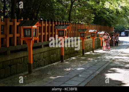 Kyoto, Japan - May 18, 2017: Orange lanterns along the pathway at Yasaka jinja shrine with walking women in kimono Stock Photo
