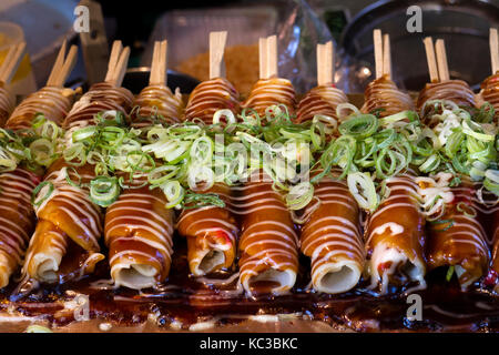 Kyoto, Japan - May 18, 2017: Baking Hashimaki,  okonomiyaki on sticks with fresh spring onions as a snack Stock Photo