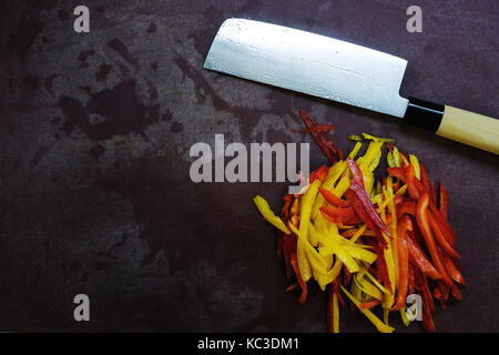 table with knife and cutted pepper. top view of kitchen equipment and fresh vegetables Stock Photo
