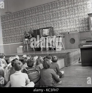 1964, historical, group of primary school children sit together watching a childrens programme on a new television set. it was at this time that childrens programming was first broadcast in the UK and the broadcasters gave away new TV sets to encourage viewing.