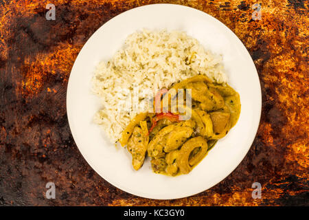 Thai Style Chicken Panang Curry With Jasmine Rice Against a Distressed Burnt Oven or Baking Tray Stock Photo