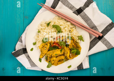 Thai Style Chicken Panang Curry With Jasmine Rice Against a Blue Wooden Background On a Tea Towel With Pink Chop Sticks Stock Photo