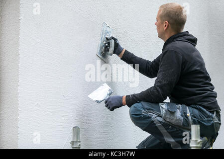 construction worker putting decorative plaster on house exterior Stock Photo