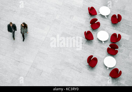 View from above of lobby with armchairs, tables and blurred pair of people passing by Stock Photo