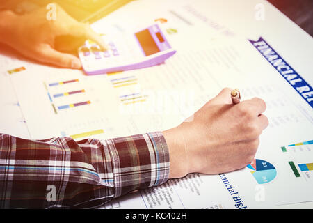 business finance accounting concept: business man hand using calculator and finance sheet report analysis on office desk Stock Photo
