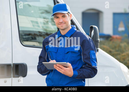 Portrait of delivery man smiling using digital tablet by truck Stock Photo
