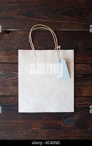 Mockup Paper bag from kraft paper with gift tag on a wooden background Stock Photo