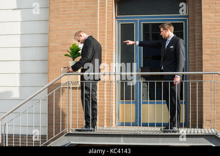 Side view of businessman firing employee carrying box with belongings outside office Stock Photo