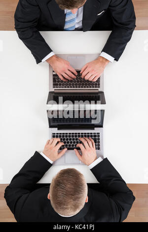 Directly above shot of businessmen using laptops at table in office Stock Photo