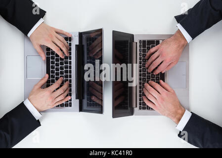 Cropped image of businessmen using laptops at white table in office Stock Photo