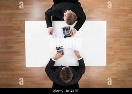 Directly above shot of businessmen using calculators at desk in office Stock Photo
