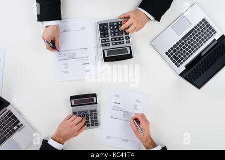 Directly above shot of businessmen calculating finance at desk in office Stock Photo