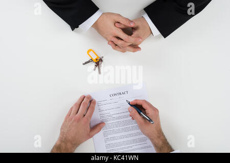 Directly above shot of real estate agent with customer signing contract at desk Stock Photo