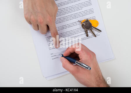 Cropped image of real estate agent assisting client to sign contract paper at desk Stock Photo