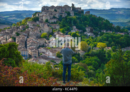 Man with camera photographing the medieval hilltop village of Cordes-sur-Ciel, in the Tarn region of Occitanie, France. Stock Photo
