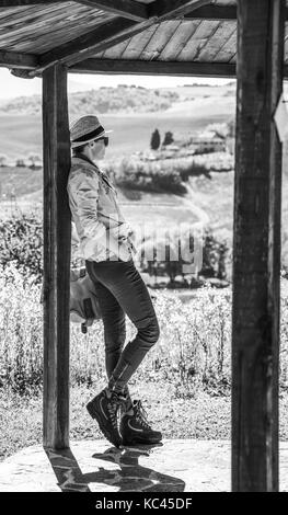 Discovering magical views of Tuscany. Full length portrait of active woman hiker in hat in Tuscany enjoying scenery Stock Photo