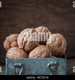 Walnuts in a small iron box. Closeup. Wooden background. Stock Photo