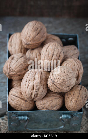 Walnuts in a small iron box and a canvas napkin. Wooden background. Stock Photo