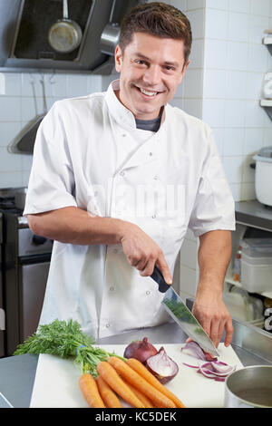 Portrait Of Chef Preparing Vegetables In Restaurant Kitchen Stock Photo