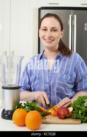 Portrait Of Woman Chopping Fruit To Put Into Juicer Stock Photo