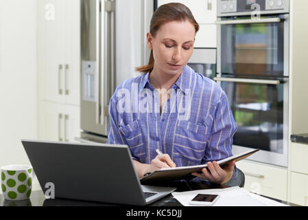 Female Freelance Worker Using Laptop In Kitchen At Home Stock Photo