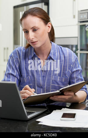 Female Freelance Worker Using Laptop In Kitchen At Home Stock Photo