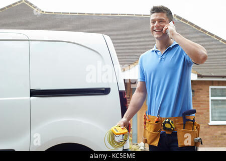 Electrician Standing Next To Van Talking On Mobile Phone Stock Photo