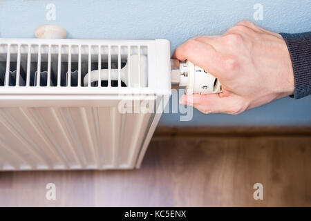 hand adjusting temperature on radiator Stock Photo
